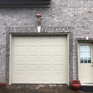 Grey brick home with a cream-colored garage door.