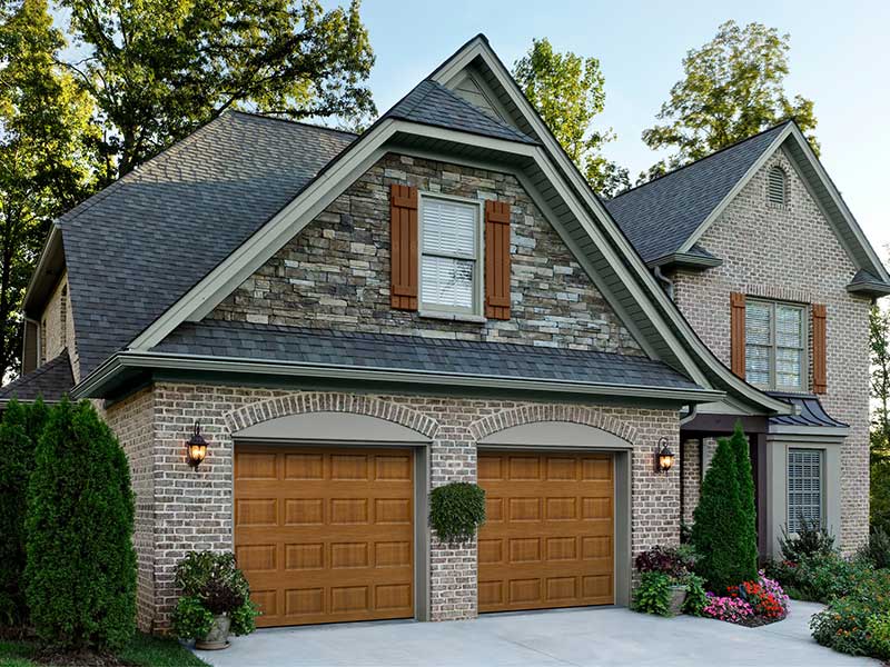 Beautiful two-story home with brick and stone siding and brown garage doors.