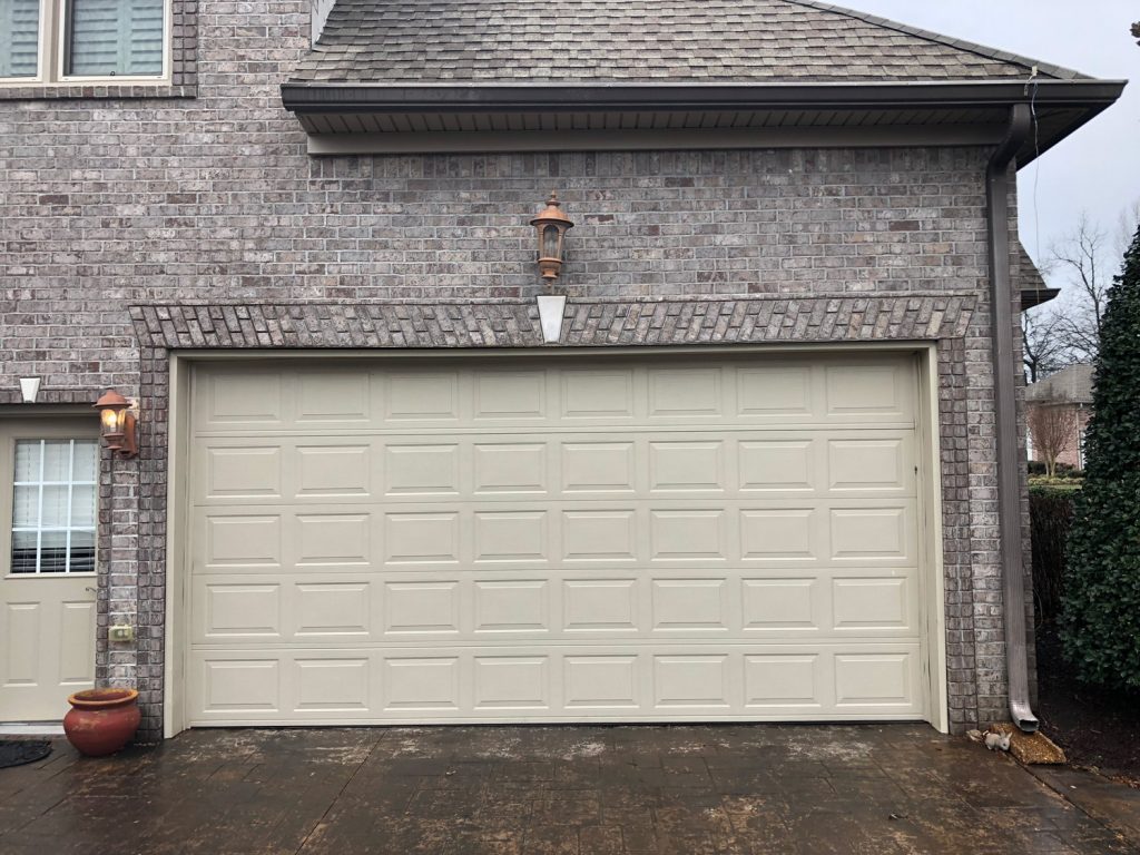 A white garage doors on a house with gray brick.