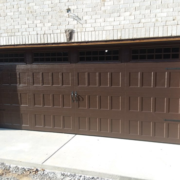 A brown garage door on a home with white brick.