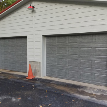 A detached garage with two separate doors in a gray color.