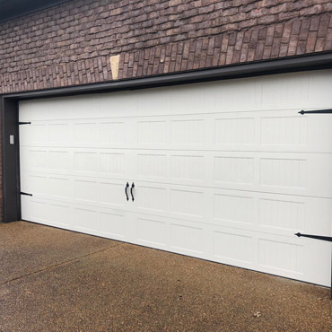A white two-car garage door on a brick home.